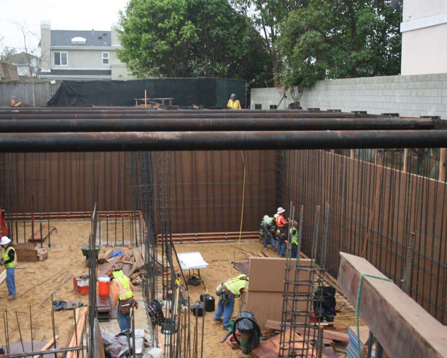 Form work and vertical ironwork for a poured in place retaining wall and basement. Pacificland Constructors