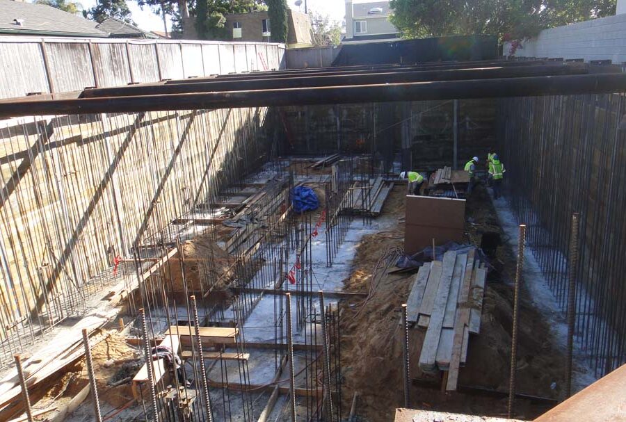 Form work and vertical ironwork for a poured in place retaining wall and basement. Pacificland Constructors