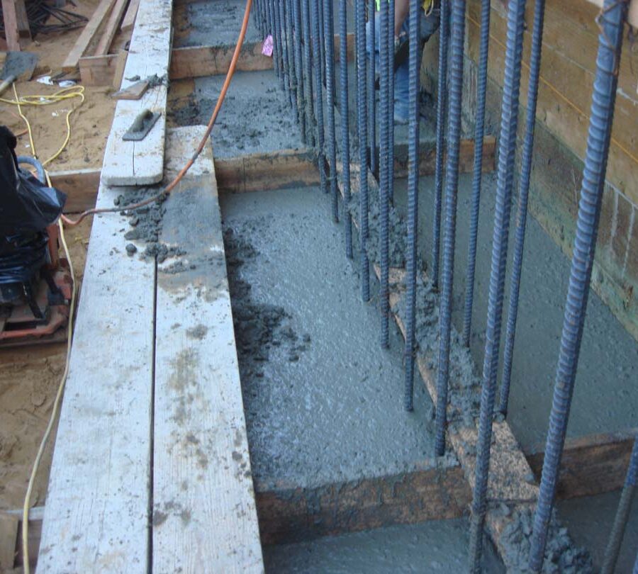 Pouring concrete into the strip footings of retaining walls. Pacificland Constructors