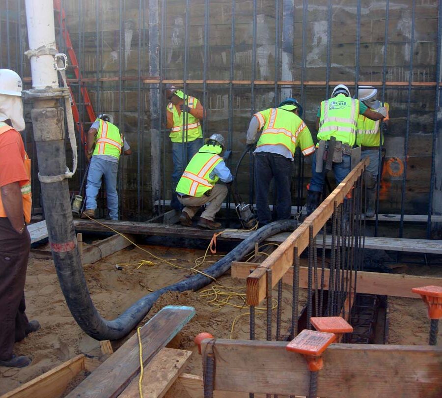 Pouring concrete into the strip footings of retaining walls. Pacificland Constructors