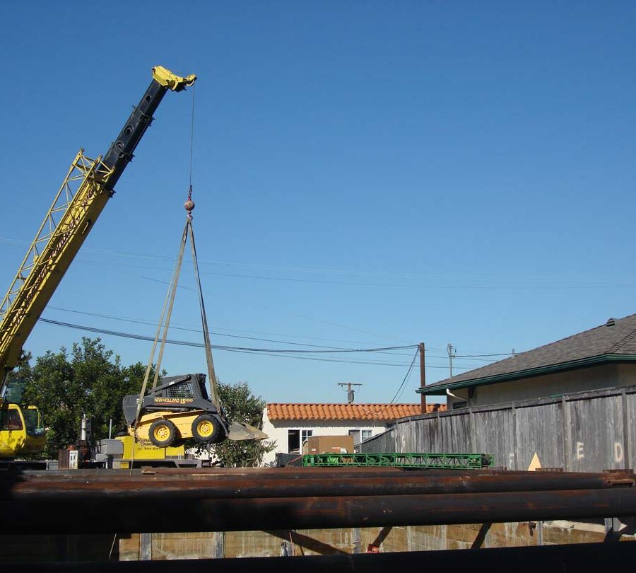 Use of a hydraulic crane to haul in a mini bobcat and steel rebar. Pacificland Constructors