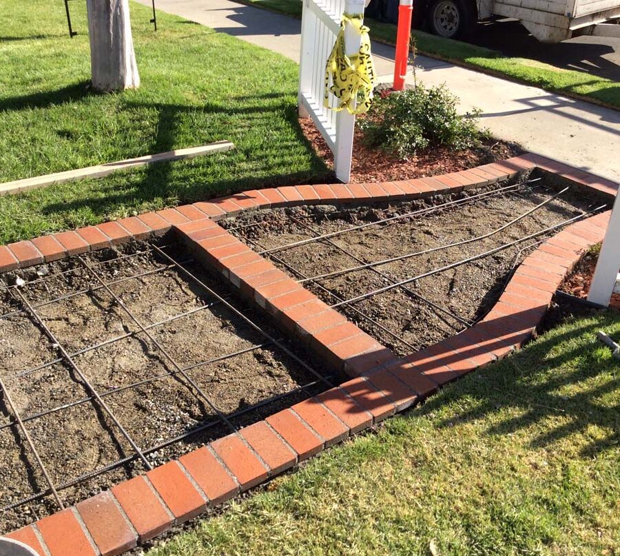 Construction of curved walkway entrance with brick ribbon and a nice brick front porch landing. The reinforced flatwork will be poured with gray concrete. Pacificland Constructors