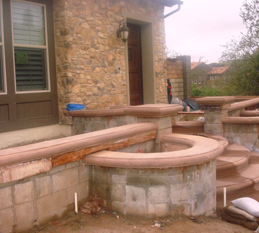 Construction of a new home entrance. New bull-nosed poured steps and CMU planters with poured wall cap prior to putting stone veneer on these planters. It had rained that weekend making a puddle where flagstone flatwork will be. Pacificland Constructors