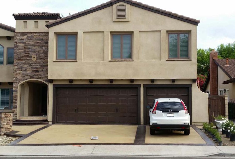 New custom entrance with colored concrete, stone veneer home, and concrete poured bull-nosed steps that contrast from the center of the slab. Pacificland Constructors