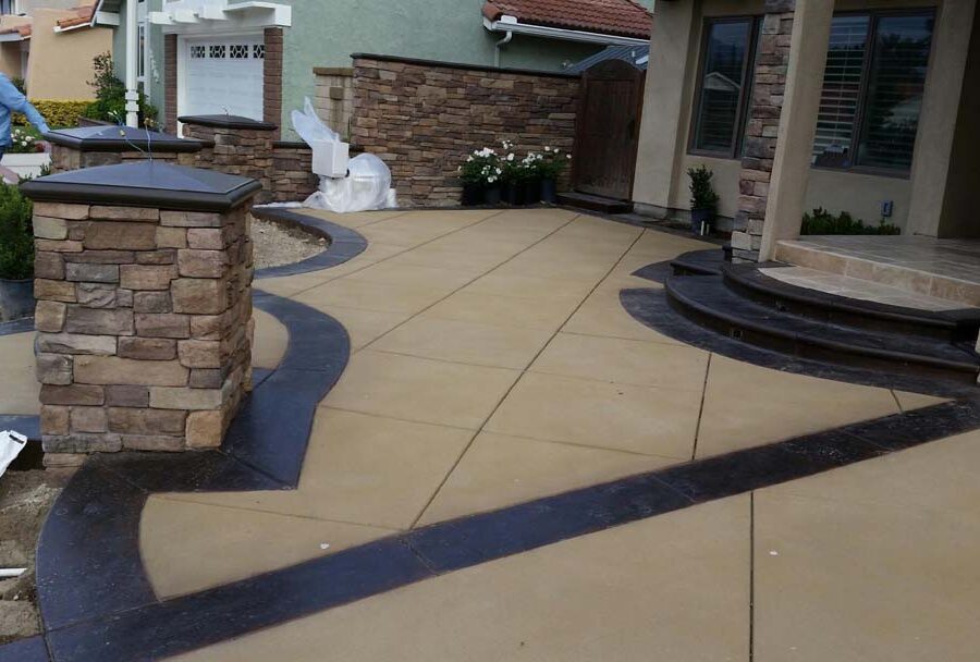 New custom entrance with colored concrete, stone covered pilasters, and concrete poured bull-nosed steps that contrast from the center of the slab.