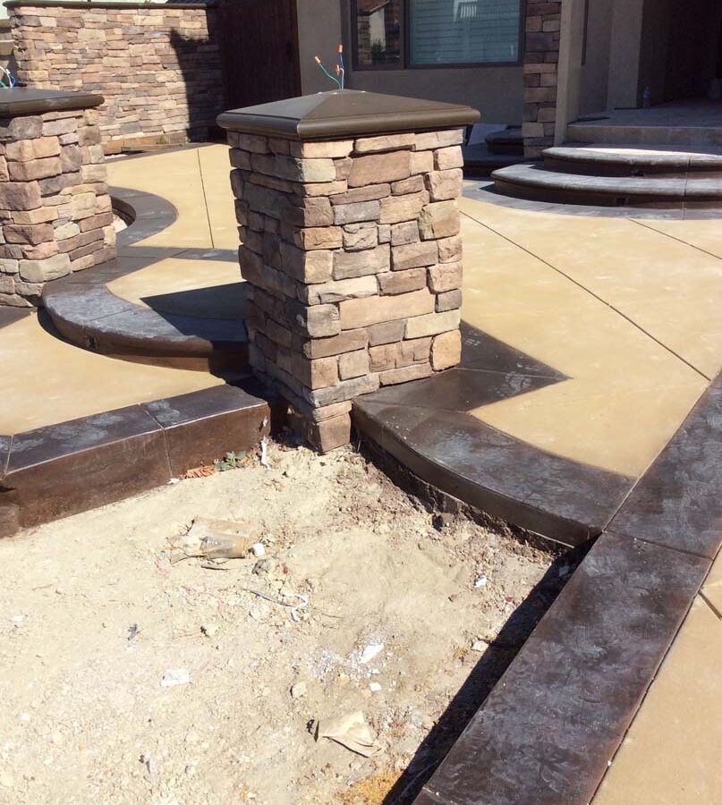 New custom entrance with colored concrete, stone covered pilasters, and concrete poured bull-nosed steps that contrast from the center of the slab. Pacificland Constructors