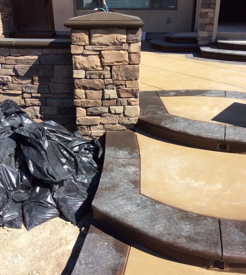 New custom entrance with colored concrete, stone covered pilasters, and concrete poured bull-nosed steps that contrast from the center of the slab. Pacificland Constructors