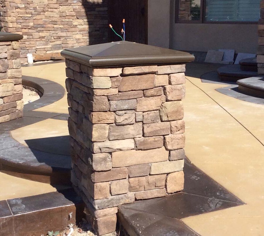 New custom entrance with colored concrete, stone covered pilasters, and concrete poured bull-nosed steps & wall cap that contrast with the light colored slab. Pacificland Constructors