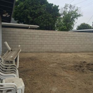 New gray colored precision freestanding wall for a backyard along the centerline of a property lines.