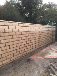 New tan colored slump block freestanding wall for a backyard along the centerlines of the property lines.