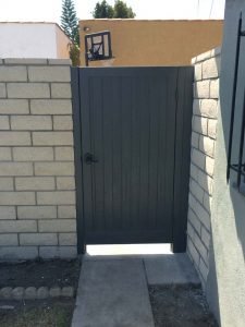 New slump block CMU wall with a wall cap for a home’s backyard. It also has access to a back alley with this wooden door.