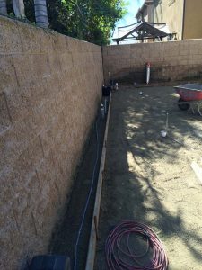 New tan colored split faced freestanding wall for a backyard along the centerline of a property line.