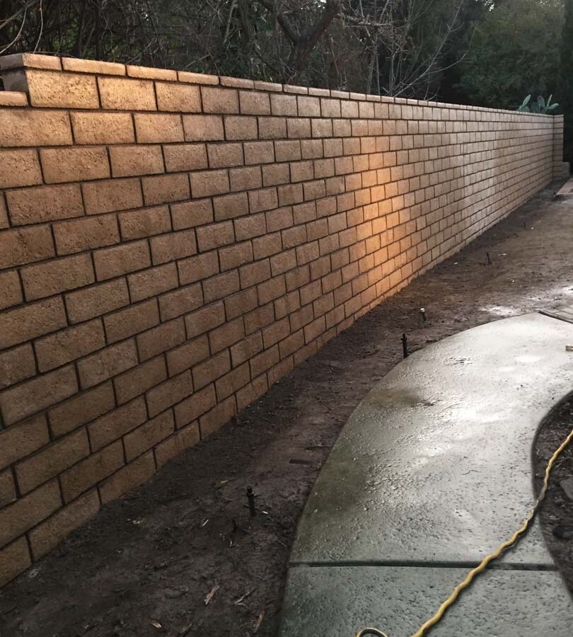 New tan colored slump block freestanding wall for a backyard along the centerline of the property lines.