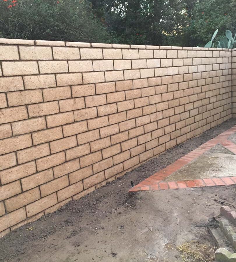 New tan colored slump block freestanding wall for a backyard along the centerline of the property lines.