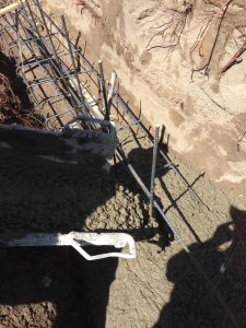Concrete pouring of strip footings for new public works curved split-faced-block freestanding wall. Pacificland Constructors