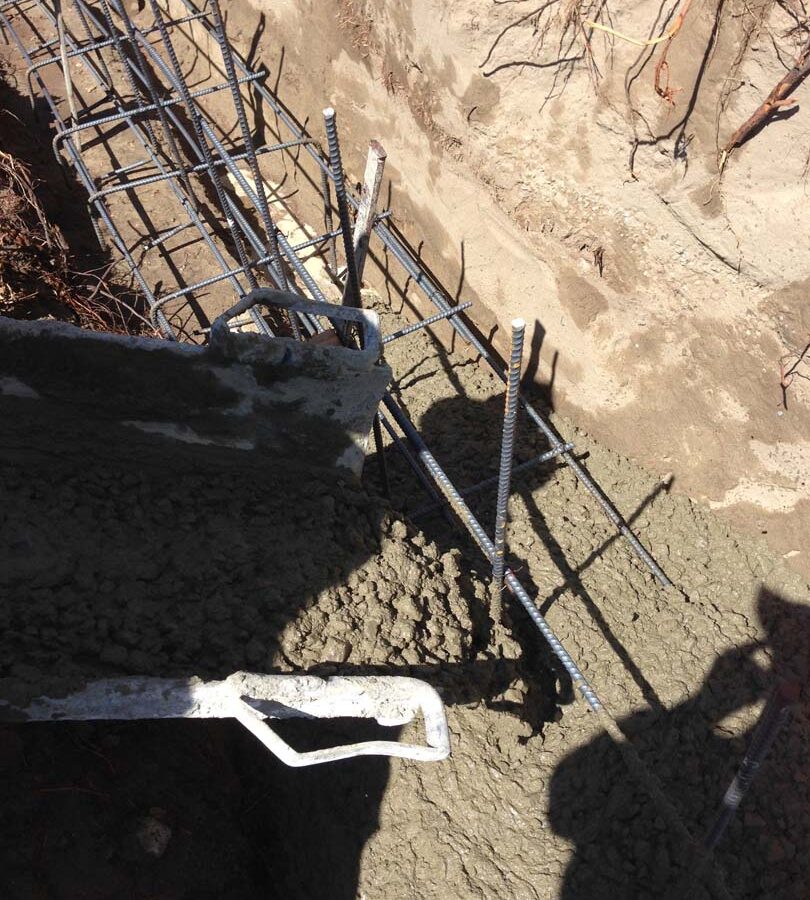 Concrete pouring of strip footings for new public works curved split-faced-block freestanding wall. Pacificland Constructors