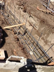 Concrete pouring of strip footings for new public works curved split-faced-block freestanding wall. Pacificland Constructors