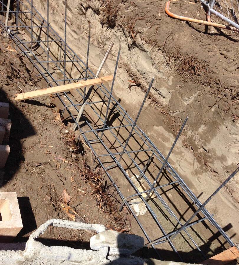 Concrete pouring of strip footings for new public works curved split-faced-block freestanding wall. Pacificland Constructors