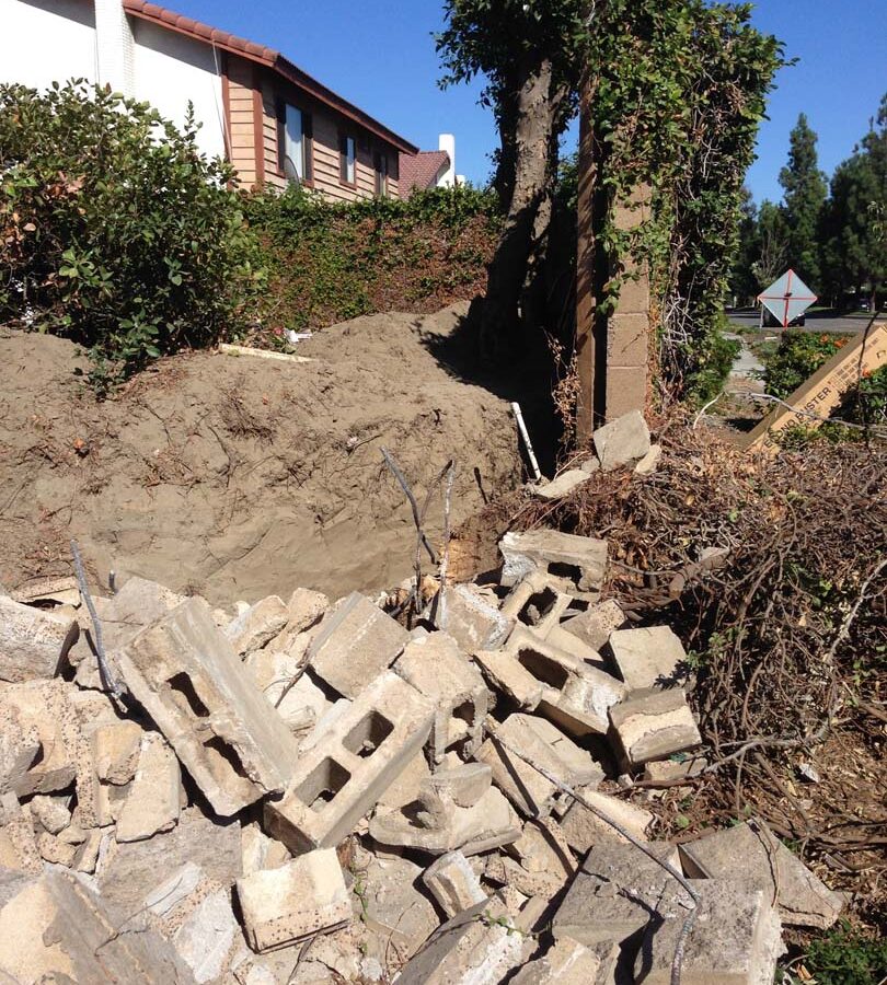 Demolition of the existing freestanding wall that was built without grout. This is an unsafe practice used by unlicensed contractors that steal money from owners by not giving them quality work. Pacificland Constructors