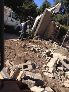 Demolition of the existing freestanding wall that was built without grout. This is an unsafe practice used by unlicensed contractors that steal money from owners by not giving them quality work. Pacificland Constructors