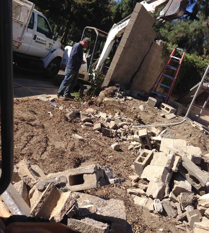 Demolition of the existing freestanding wall that was built without grout. This is an unsafe practice used by unlicensed contractors that steal money from owners by not giving them quality work. Pacificland Constructors