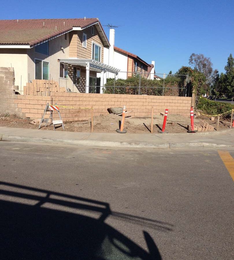 Construction of a new curved split-faced-block freestanding wall for public works. Pacificland Constructors