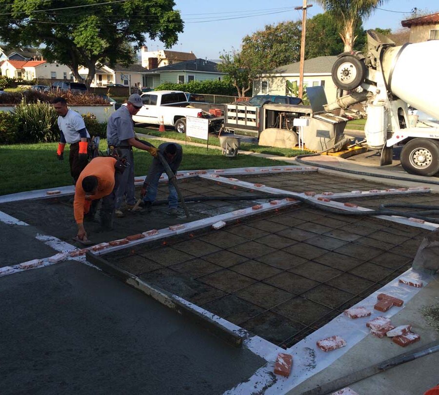 Pouring a new gray concrete driveway with brick ribbons. Pacificland Constructors