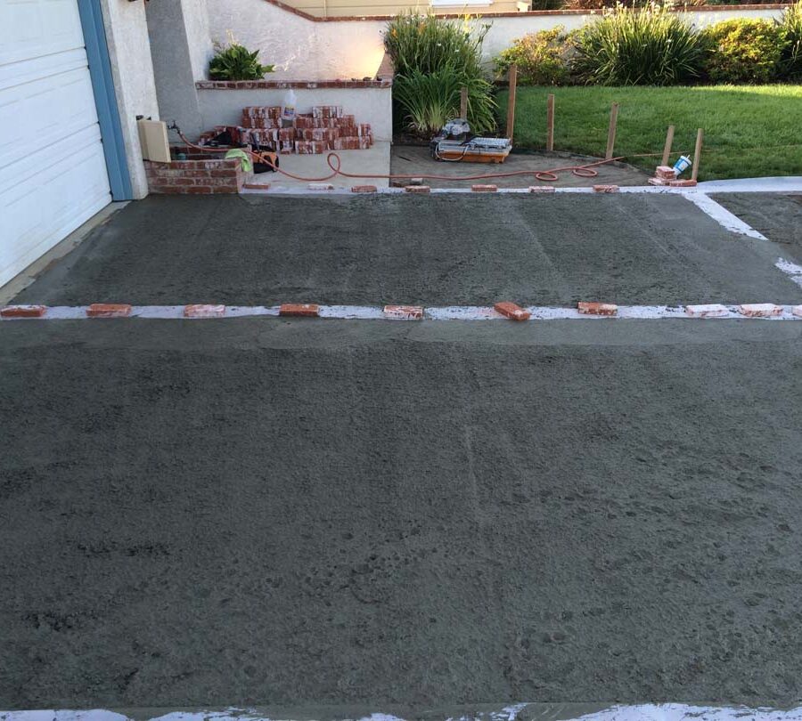 Pouring a new gray concrete driveway with brick ribbons. Pacificland Constructors