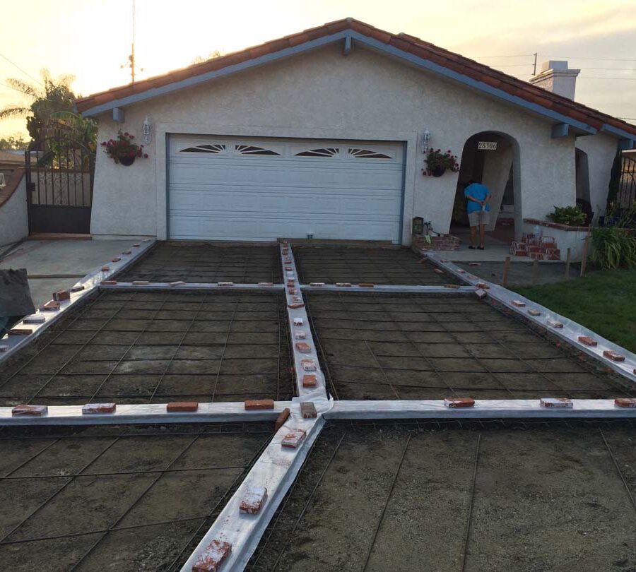 Installing steel reinforcement of a new gray concrete driveway with brick ribbons. Pacificland Constructors