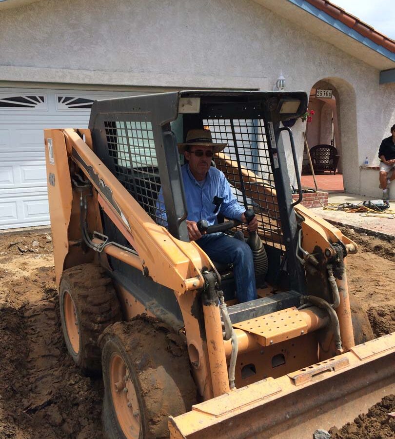 Founder of Pacificland, Martin, using a machine to demolish the outdated driveway.