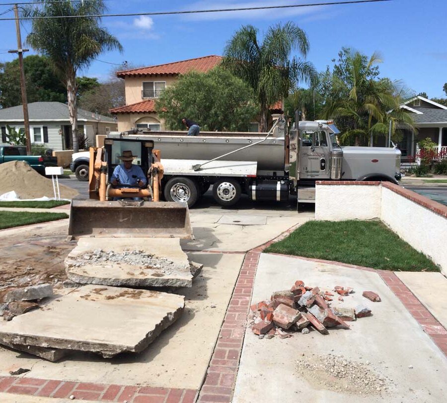 Founder of Pacificland, Martin, using a machine to demolish the outdated driveway.