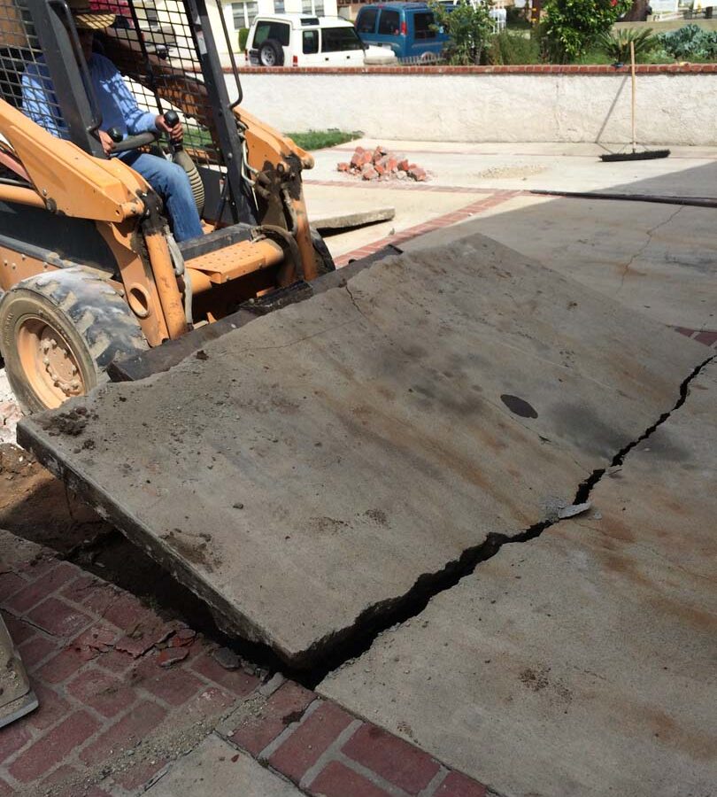 Founder of Pacificland, Martin, using a machine to demolish the outdated driveway.