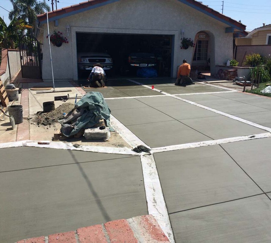 New broom swept gray concrete driveway with brick ribbons. Pacificland Constructors