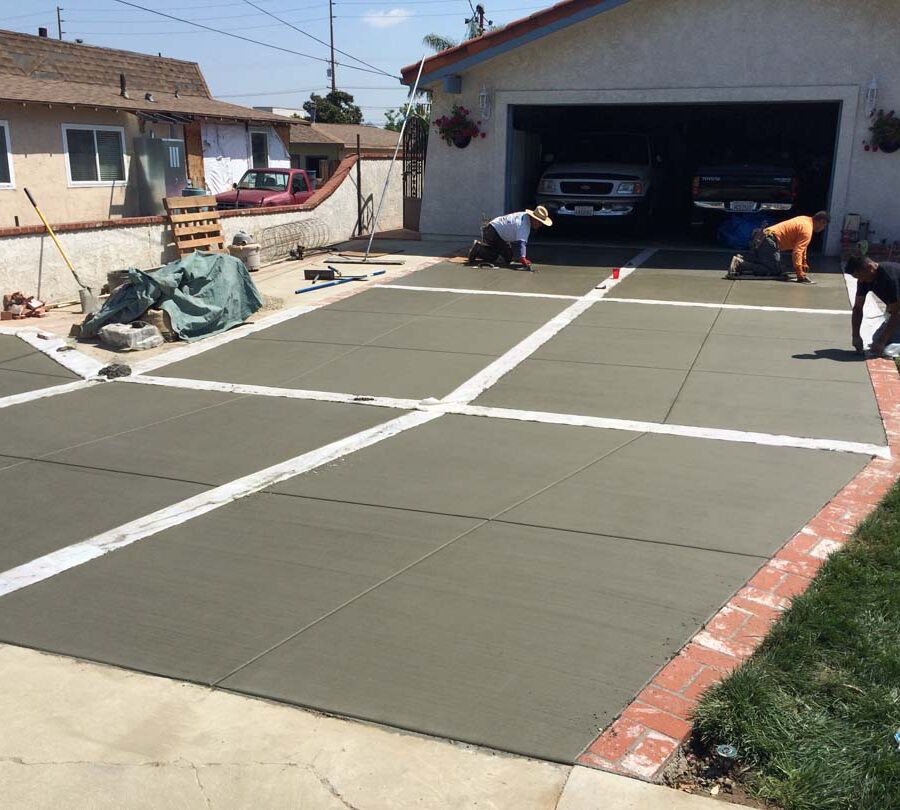 New broom swept gray concrete driveway with brick ribbons. Pacificland Constructors