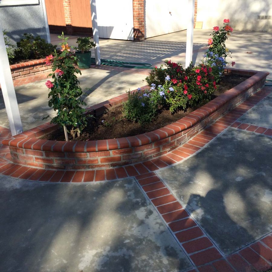 New concrete slab with brick ribbon and brick planters. Pacificland Constructors