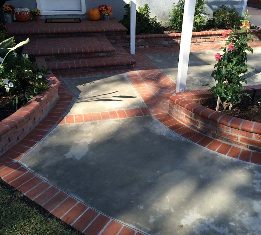 New concrete slab with brick ribbon and brick planters. Pacificland Constructors