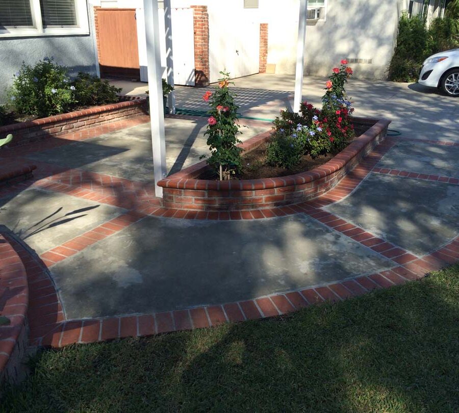 New concrete slab with brick ribbon and brick planters. Pacificland Constructors