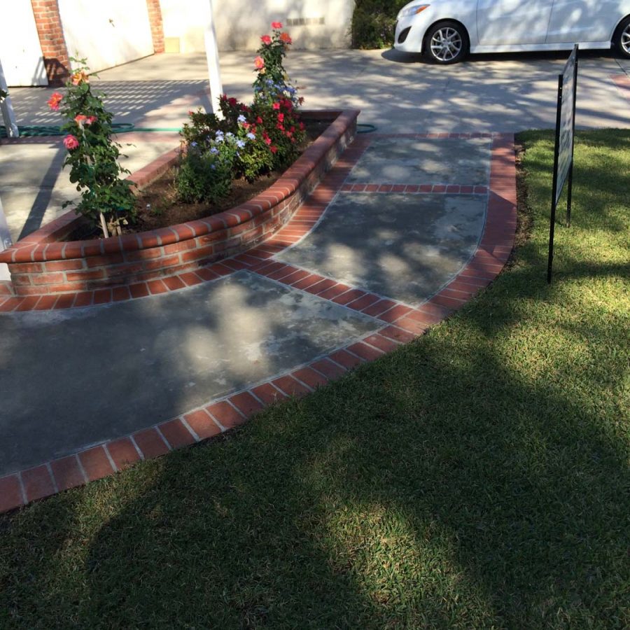 New concrete slab with brick ribbon and brick planters. Pacificland Constructors