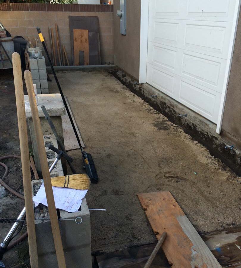 Grading and steel dowel into existing garage slab for a new broom swept concrete backyard patio. Pacificland Constructors