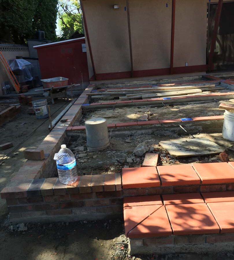 Construction of bull-nosed steps for a new broom swept gray concrete patio with brick ribbons. Pacificland Constructors