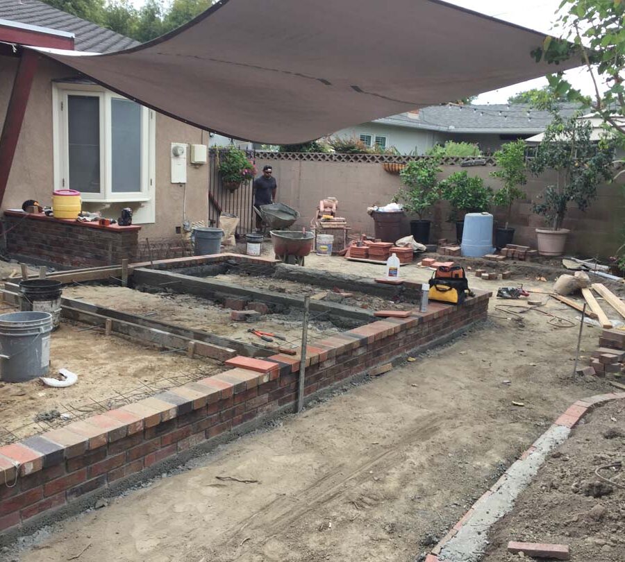 Construction of a new raised gray concrete patio with brick ribbons. Pacificland Constructors