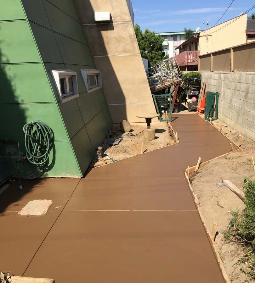 New backyard colored concrete walkway on the sides and backyard with hand scorched joints. Pacificland Constructors