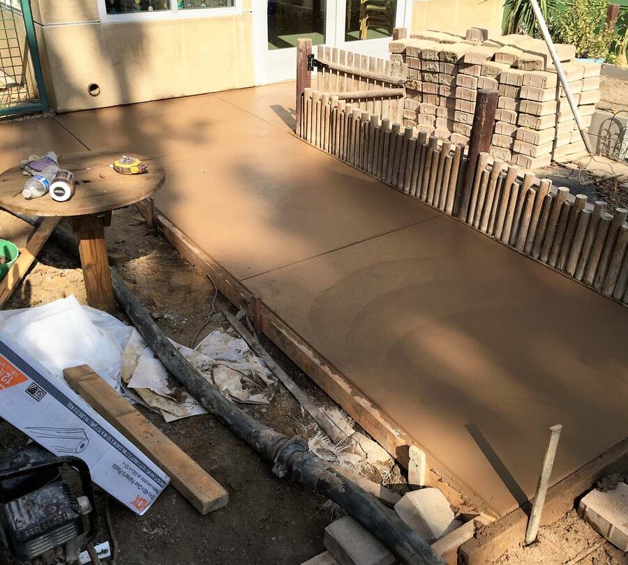 New backyard colored concrete walkway on the sides and backyard with hand scorched joints. Pacificland Constructors