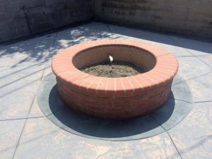 This new brick fire pit will be gas powered and have fire-glass to hold the heat. Its contrast in material makes it stand out from the rest of the concrete work.
