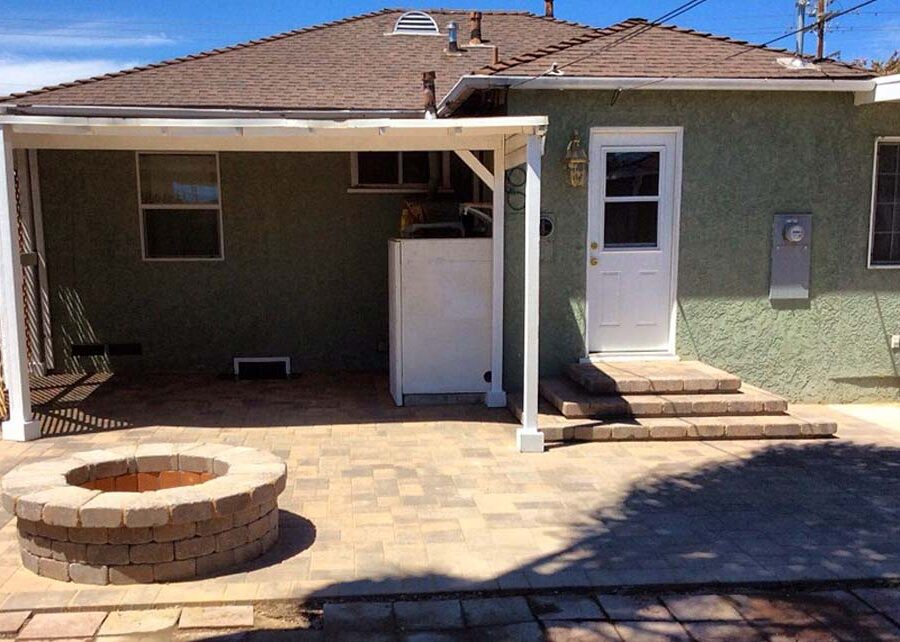 New backyard patio, steps, landing, and firepit built with colored concrete pavers for a residential project.