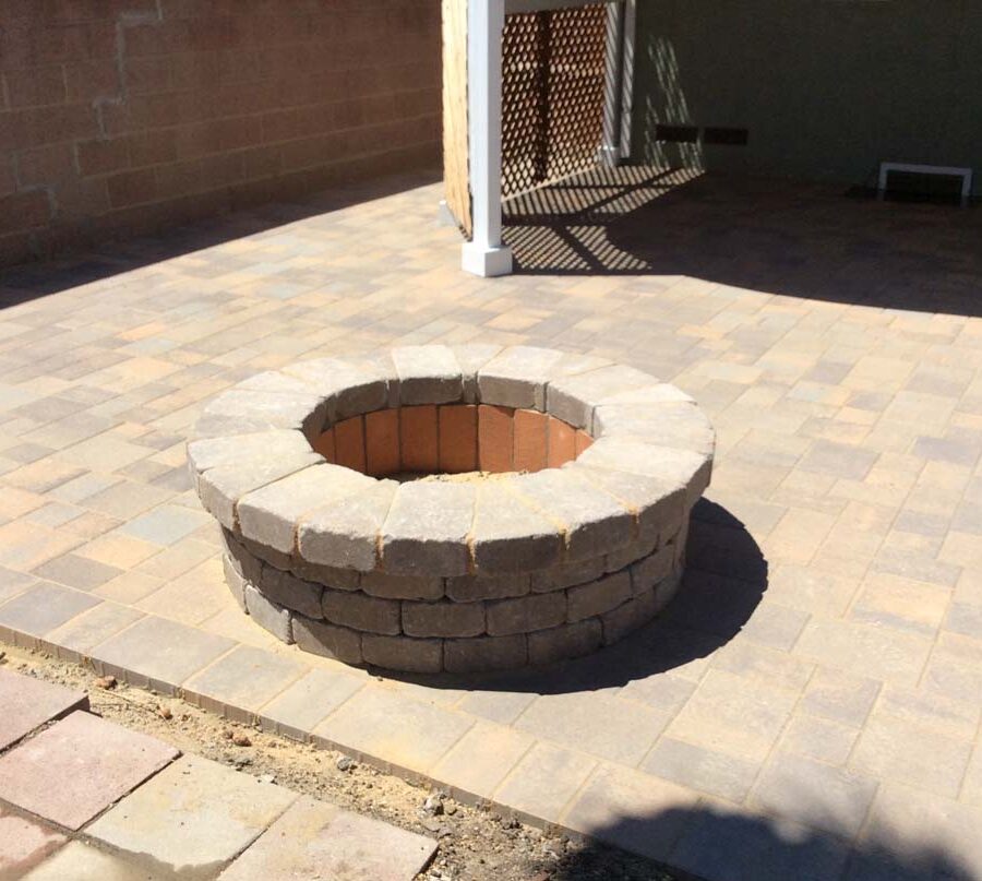 New backyard patio and firepit built with colored concrete pavers for a residential project.