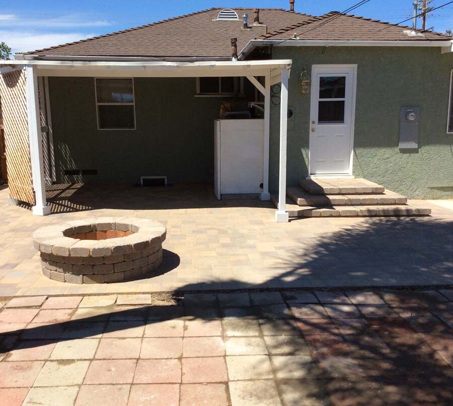 New backyard patio, steps, landing, and firepit built with colored concrete pavers for a residential project.