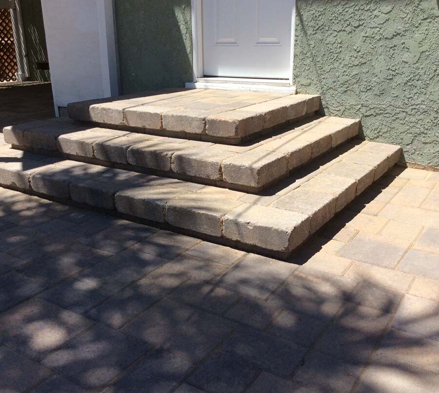 New backyard patio, steps, and landing built with colored concrete pavers for a residential project.