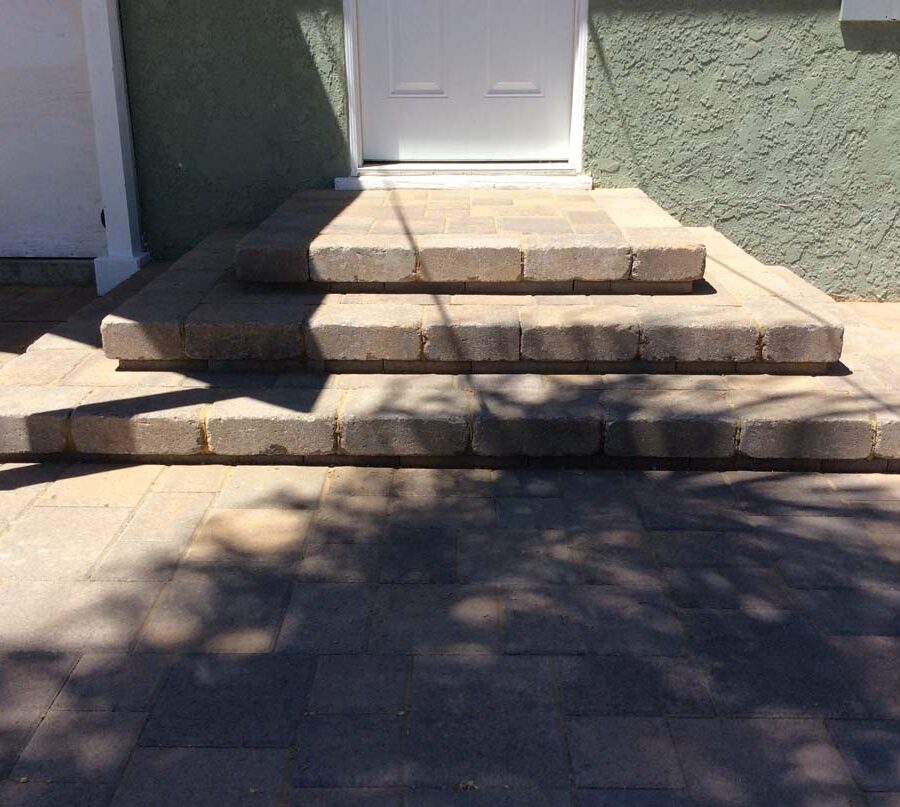 New backyard patio, steps, and landing built with colored concrete pavers for a residential project.