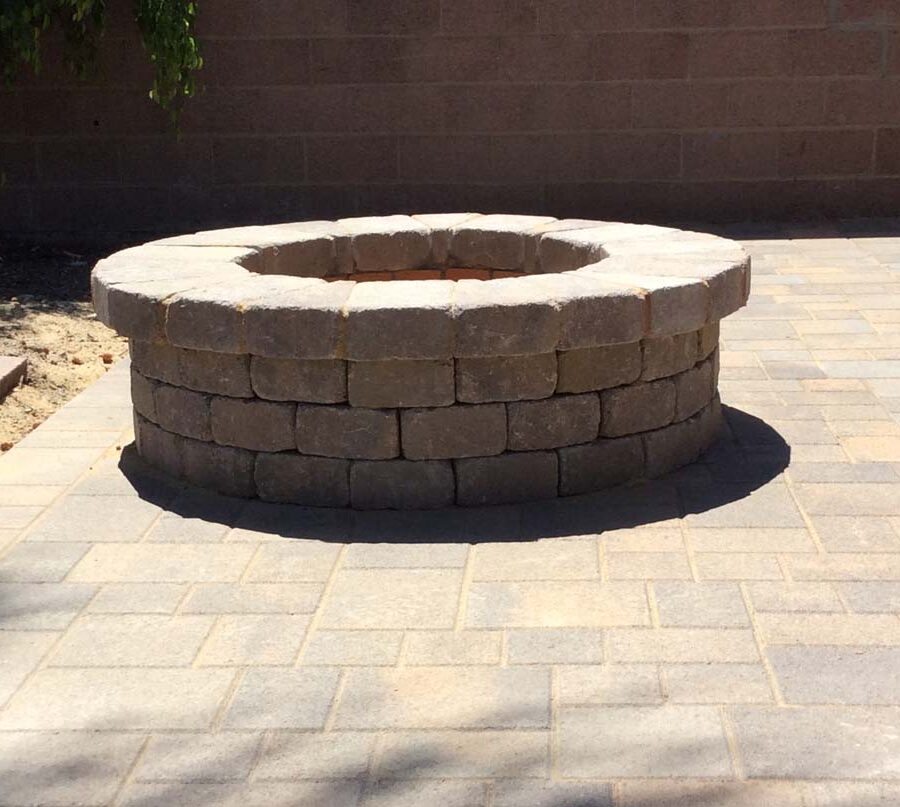 New backyard patio and firepit built with colored concrete pavers for a residential project.